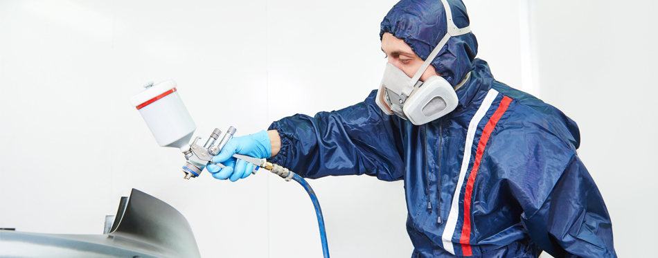 man wearing respiratory protection using sprayer